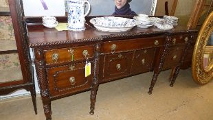 A George III Irish mahogany sideboard with an arrangement of drawers and cupboards having lion