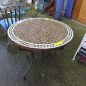 A mosaic garden table on wrought iron base and two chairs