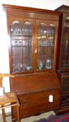 An early C20th mahogany bureau bookcase with arched glazed panel doors above fall front and