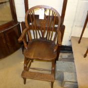 A C19th Windsor oak and beech high chair with wheel back above solid seat on stretchered turned