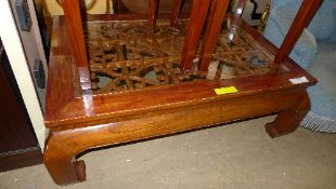 A Chinese lacquered low table with glass top and carved decoration