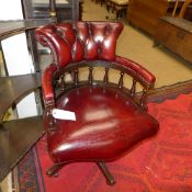 A mid C20th mahogany swivel captain chairs upholstered in red button leather raised on castors