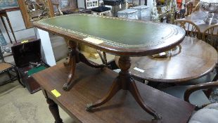 A C20th mahogany low table with leather inset on twin pedestal bases