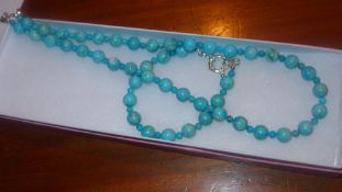 A silver and turquoise beaded necklace and bracelet set