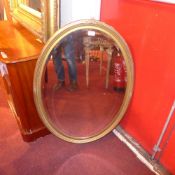 An oval wall mirror the bevelled plate within carved giltwood frame