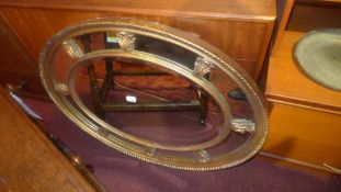 An oval looking glass with divisional giltwood frame