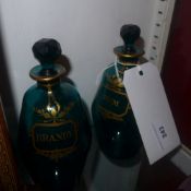 A pair of Regency green glass decanters and stoppers with gold hand painted detail