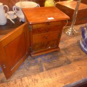 A tabletop cabinet with parquetry inlaid panel door opening to reveal four drawers