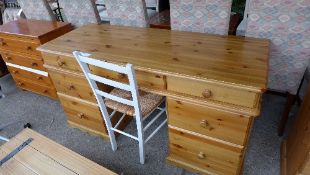 A pine pedestal desk with assorted drawers