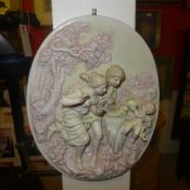 A pair of wall hanging plaques depicting courting couples