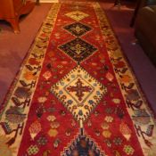 A fine South West Persian Qashgai runner 335 x 83 cm repeating goul motifs on a terracotta field