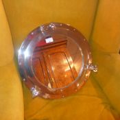 A chrome framed porthole style wall mirror with circular plate