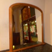 A pine framed overmantel mirror with arched plate