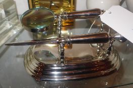 A chromed desk stand with letter opener and magnifying glass