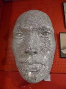 A wall mounted mirrored crackleglaze style model of a face