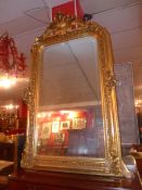 A French wall mirror with arched bevelled plate within ornate gilt frame