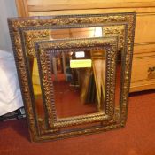 A late C19th wall mirror with bevelled plate within mirrored cushion border and having copper mounts
