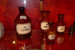 A set of four labelled brown apothecary jars of various sizes with glass stoppers