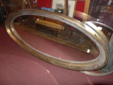 A large oval wall mirror in a moulded gilt frame