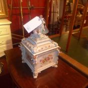 A Meissen style porcelain liddled casket with cherubs and floral decoration in relief and heightened