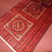 A fine North East Persian Turkoman rug 240 x 130 cm repeating goul motifs on a rouge field within