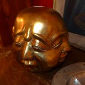 A gold painted Buddha head displaying four expressions