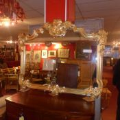A wall mirror with shaped plate within ornate leafy gilt frame