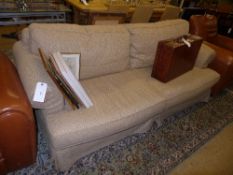 A two seater sofa upholstered in beige fabric on bun feet