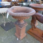 A pair of large terracotta campana style garden urns on plinths