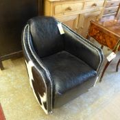 A leather/cowhide tub chair with studded detail raised on castors