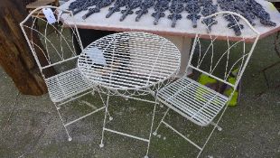 A wrought iron patio set comprising folding table and chairs