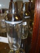 A pair of silver plate and glass cocktail shakers with recipes