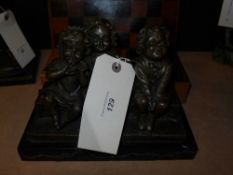 A bronze cast of three chubby children sat on a bench marked Juan Clara, on a rectangular marble