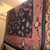 A hand made Persian carpet with a terracotta medallion on a midnight blue field surrounded by a