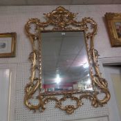 A Florentine style giltwood wall mirror in scrolling leafy frame