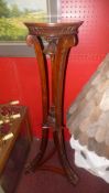 A pair of carved mahogany torcheres on swept triple supports