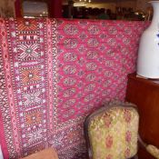 A Bokhara style carpet with many guls on a red field surrounded by one frieze and several running