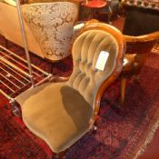 A Victorian carved walnut nursing chair upholstered in buttoned green velour on cabriole supports