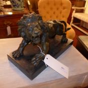 A pair of bronze lions on black marble pedestal bases