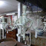 A white painted wrought iron six branch chandelier with acanthus leaf relief