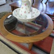 A G-plan teak circular table with glass inset top on shaped supports