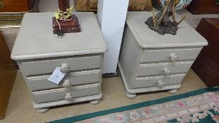 A pair of painted bedside chests with three drawers on bum feet
