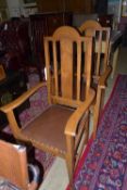 A pair of oak open elbow chairs with pad seat and raised on tapering supports