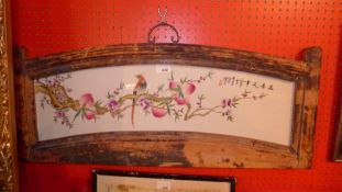 A Chinese famille rose porcelain plaque decorated with a bird and peaches in a wooden frame