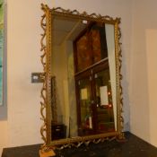 A pair of Georgian style gilt wall mirrors with carved and pierced leafy frames