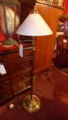A brass reading lamp with opaque glass shade on adjustable supports