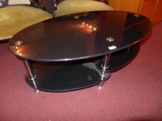 A smokey glass two tier low table on chromed supports
