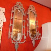A pair of wall mirrors in distressed finish frames with triple sconces