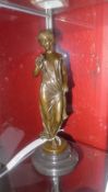 A bronze of a maiden holding flowers on black marble base
