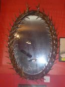 An oval wall mirror within faux antler style frame